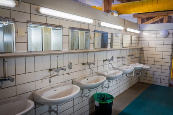 Sanitäreinrichtungen Helle Männerumkleide mit Waschbecken und Spiegeln an der Wand.