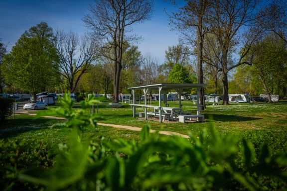 Zeltplatz mit Gemeinschafts Verweilmöglichkeiten Blick auf einen Campingplatz mit grüner Landschaft und Bäumen im Hintergrund.