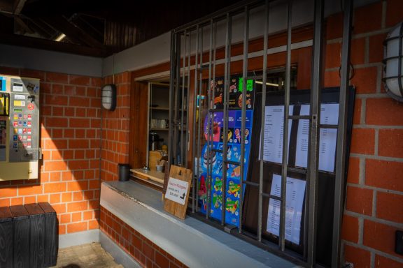 Kiosk Eingang zu einem Kiosk mit Gitter und bunten Plakaten an der Wand.